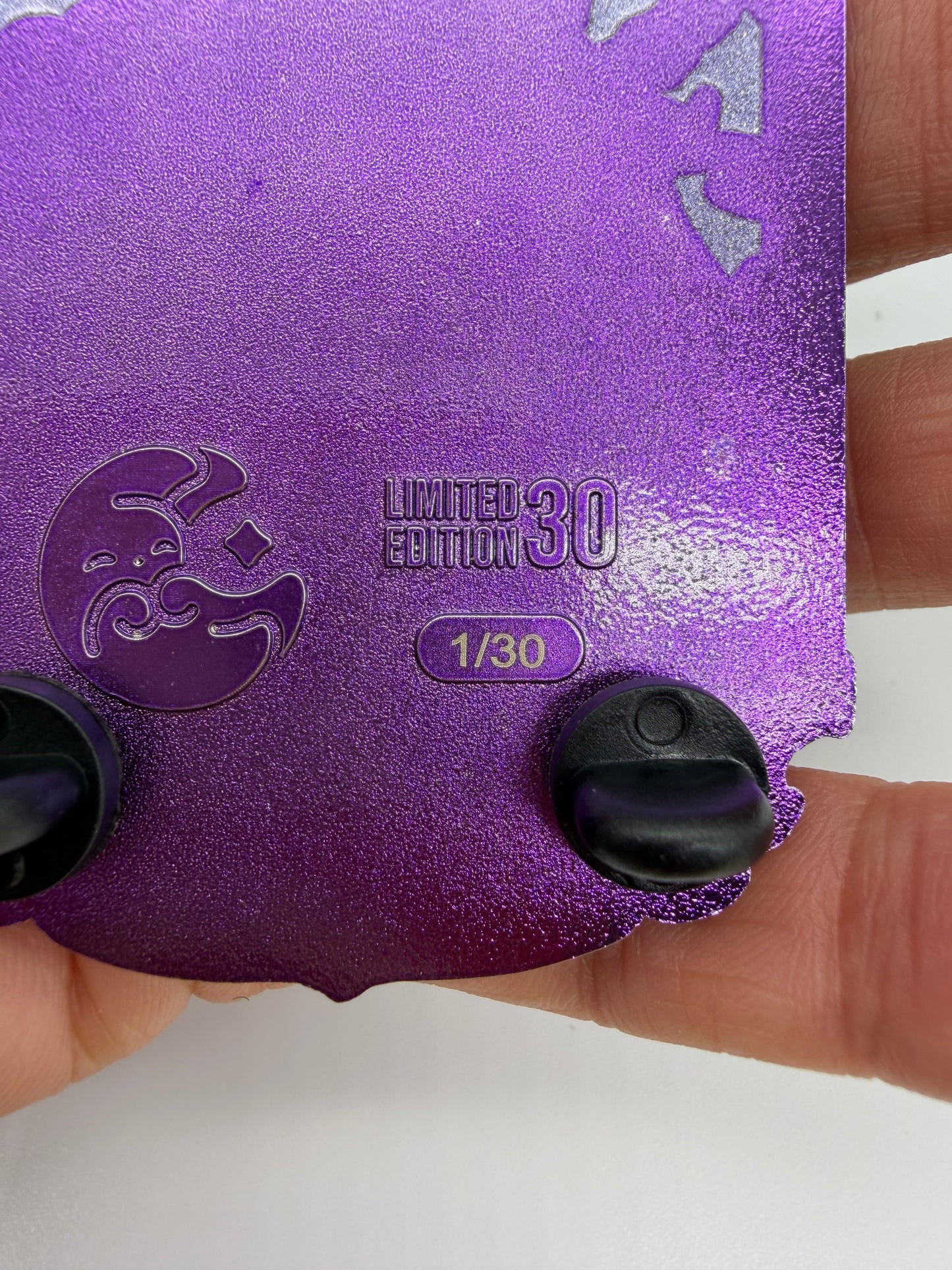 A close-up of a purple glittery collectible card or sticker being held by a hand. The card features a crescent moon emblem, the text 'LIMITED EDITION 30' and '1/30', and two black plastic tabs on the bottom edge.