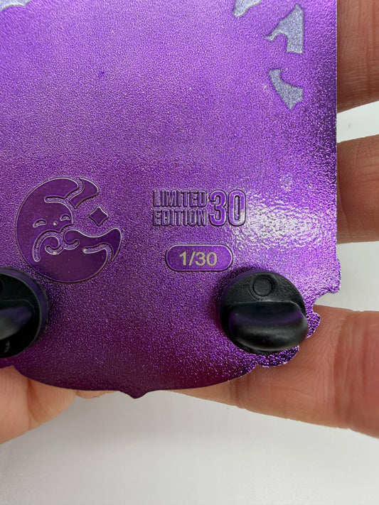 A close-up of a purple glittery collectible card or sticker being held by a hand. The card features a crescent moon emblem, the text 'LIMITED EDITION 30' and '1/30', and two black plastic tabs on the bottom edge.